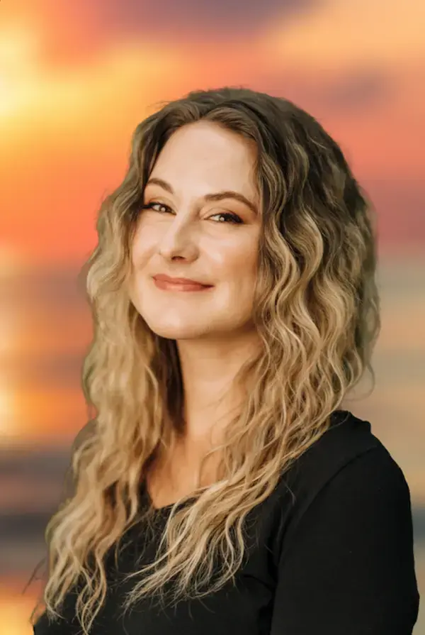 Dr Allison Champagne smiling in front of a sunrise background