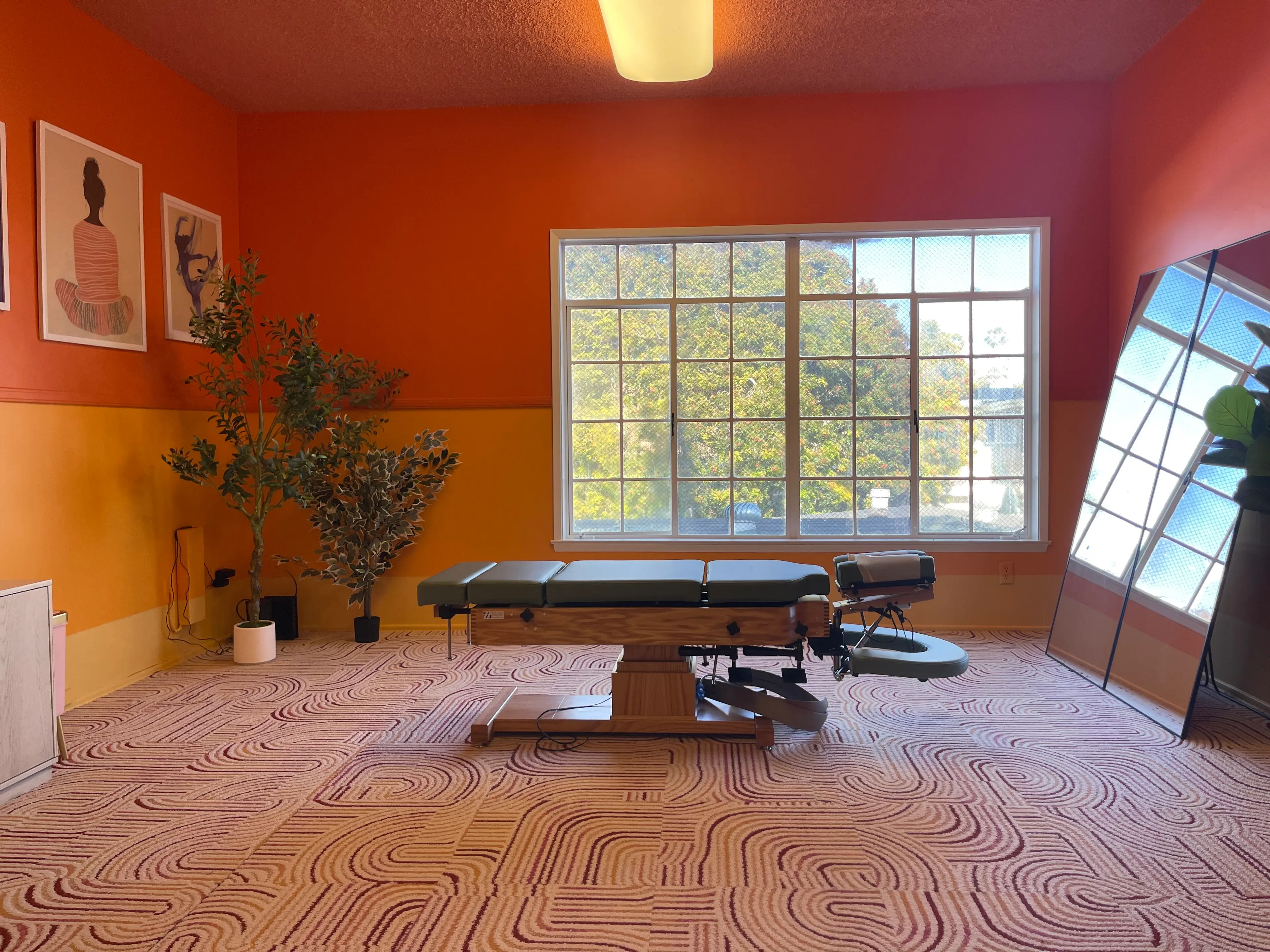 Pacific Beach Chiropractic from the front, including chiropractic table, sunset colored walls, and view out window.